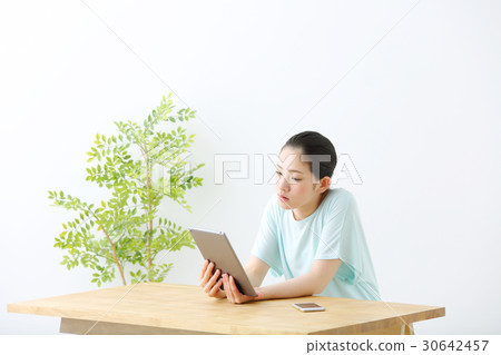 A woman watching a tablet A woman watching a tablet 30642457