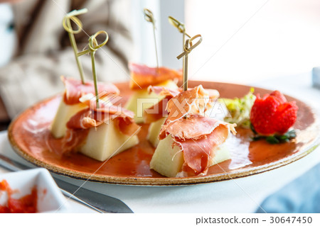 Melon with Serrano ham lay on the plate. 30647450