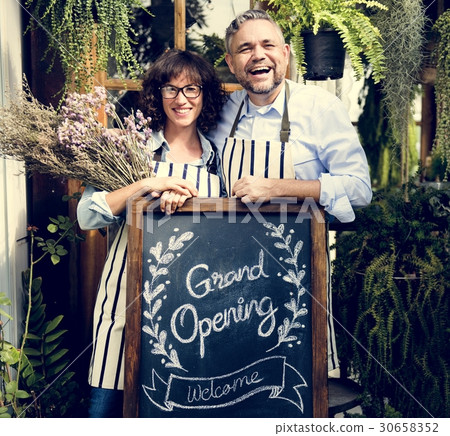 Adult Man and Woman Standing with Grand Opening Sign Adult Man and Woman Standing with Grand Opening Sign 30658352