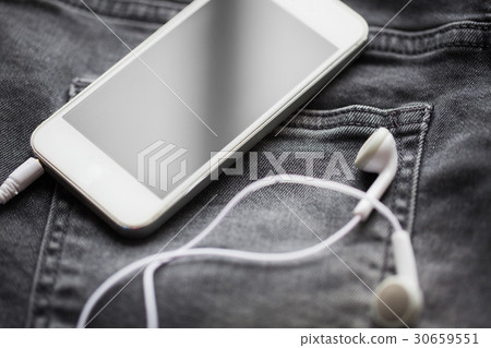smartphone and earphones on denim or jeans pocket 30659551