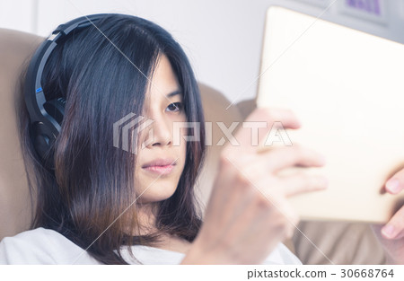 girl with headphone is watching content on tablet 30668764