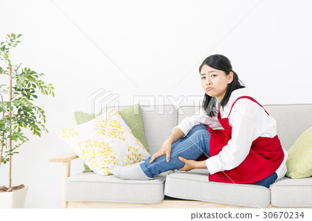 Housewife suffering from pain in the legs sitting on the sofa Housewife suffering from pain in the legs sitting on the sofa 30670234