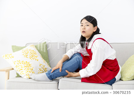 Housewife suffering from pain in the legs sitting on the sofa 30670235