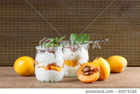 Fresh yogurt with loquats on rustic background Fresh yogurt with loquats on rustic background 30673188