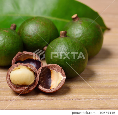 macadamia nuts isolated on wooden background 30675446