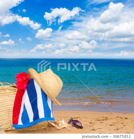 sunbathing accessories on sandy beach in straw bag 30675851