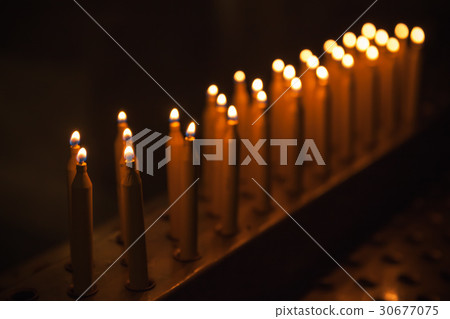 Burning prayer candles stand in a row Burning prayer candles stand in a row 30677075