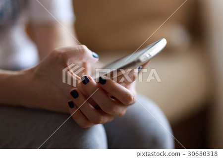 Woman holding smartphone, looking at screen, using 30680318