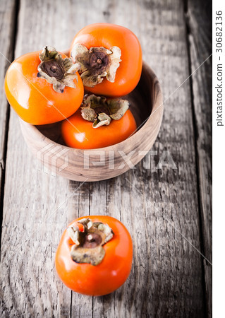 Persimmons on a wooden table Persimmons on a wooden table 30682136