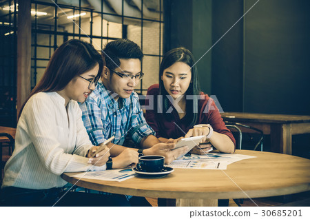 Group Of Asian Business people with casual suit Meeting in looking at the smart phone action In the modern coffee shop, business group concept Group Of Asian Business people with casual suit Meeting in looking at the smart phone action In the modern coffee shop, business group concept 30685201