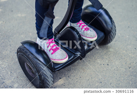 girl's legs wearing sneakers riding gyroscooter or girl's legs wearing sneakers riding gyroscooter or 30691116