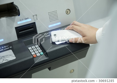 A young woman holding the cell phone on the automatic check-in machine 30691285