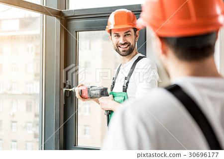 Happy smiling constructor working with puncher 30696177