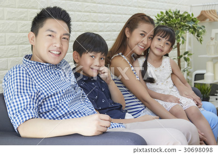 parents and their kids are sitting and looking at the camera. parents and their kids are sitting and looking at the camera. 30698098