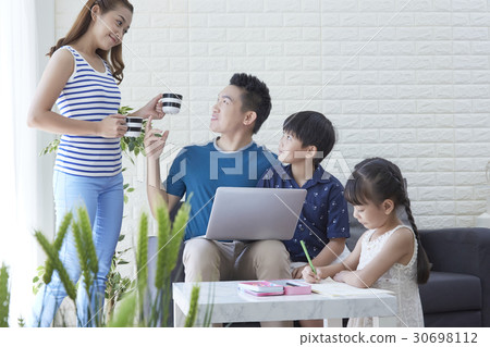 mother is giving water to father and son while daughter is drawing. 30698112