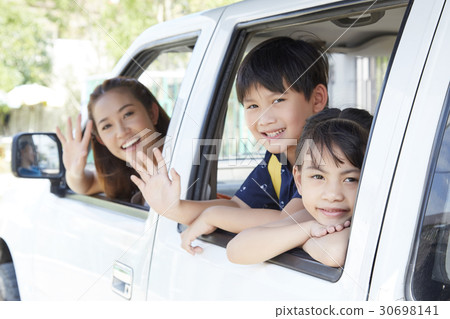 mother and two kids are waving to say good bye from the car. 30698141