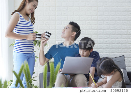 mother is giving water to father while kids are studying. mother is giving water to father while kids are studying. 30698156