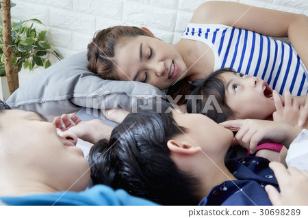 a family of parents and two children lying and sleeping 30698289