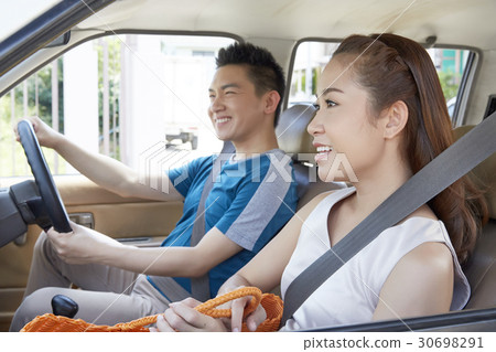 a photo of a couple sitting, smiling and driving car 30698291