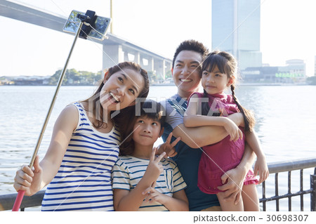 A photo of a happy family of four people taking selfie outdoor 30698307