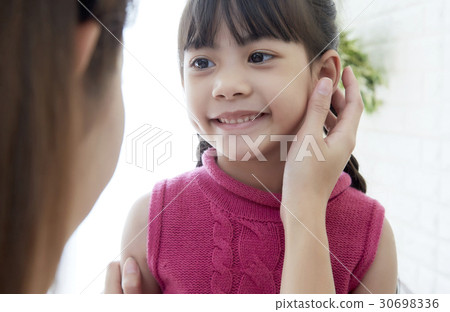 A portrait of a cute girl whose face is touched by a woman A portrait of a cute girl whose face is touched by a woman 30698336