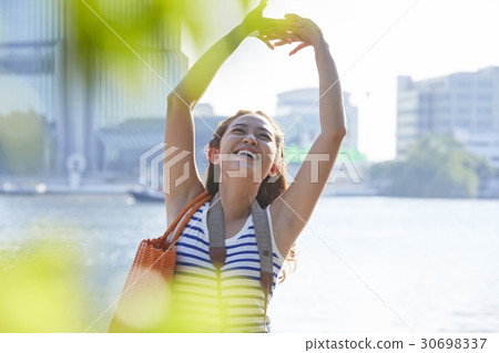 A girl is smiling and rising arms up beside a river. A girl is smiling and rising arms up beside a river. 30698337
