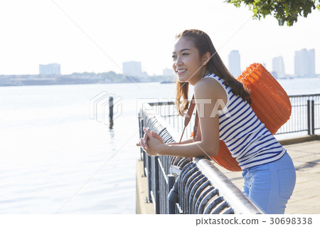 A girl is standing, smiling and viewing scene on a riverside. 30698338
