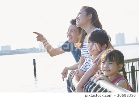 Parents and two kids are smiling and viewing on a riverside. Parents and two kids are smiling and viewing on a riverside. 30698356