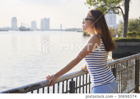 The left side of a girl standing and viewing sunrise on a riverside 30698374
