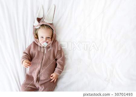 Cute baby in romper on bed Cute baby in romper on bed 30701493