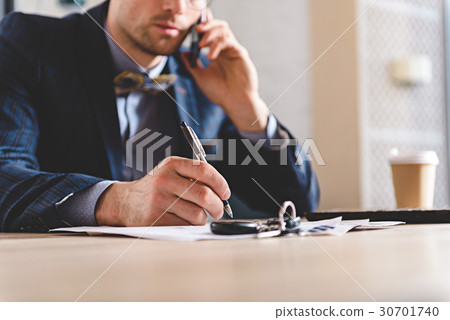 male writing at table while talking on phone male writing at table while talking on phone 30701740