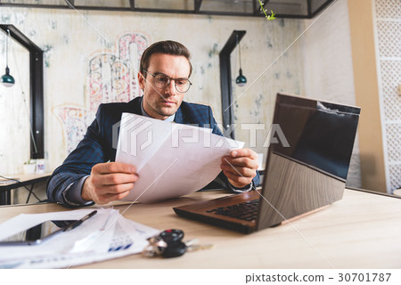 Orderly male reading documents in room 30701787