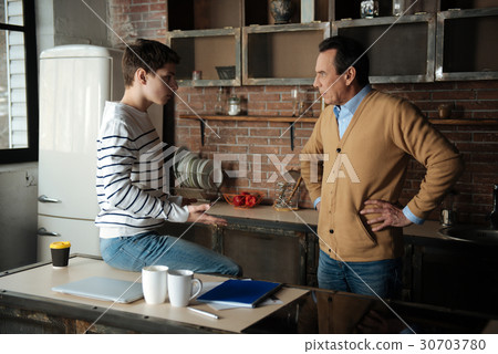 Delighted boy sitting on the table 30703780