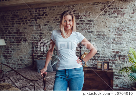 Attractive blonde woman is standing at home near Attractive blonde woman is standing at home near 30704010