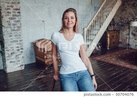 Attractive blonde woman in a white t-shirt sits at Attractive blonde woman in a white t-shirt sits at 30704076