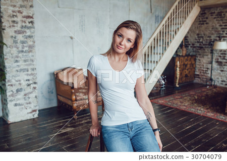Attractive blonde woman in a white t-shirt sits at Attractive blonde woman in a white t-shirt sits at 30704079