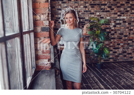 Beautiful blonde woman in a gray dress is standing Beautiful blonde woman in a gray dress is standing 30704122