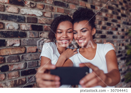 Two attractive African girls make selfie at home. Two attractive African girls make selfie at home. 30704441