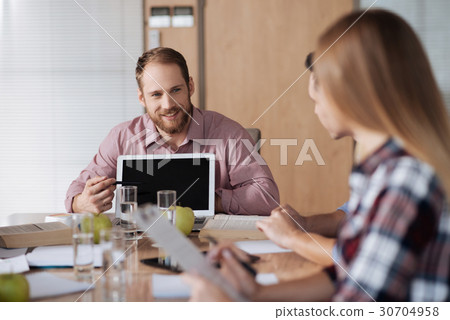 Positive delighted bearded man sitting behind his Positive delighted bearded man sitting behind his 30704958