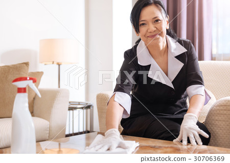 Joyful professional hotel maid sitting in the 30706369