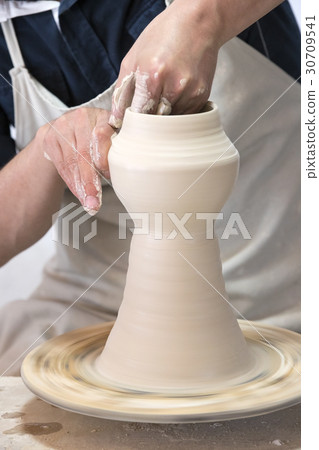 Potter makes pottery handmade in the workshop  30709541