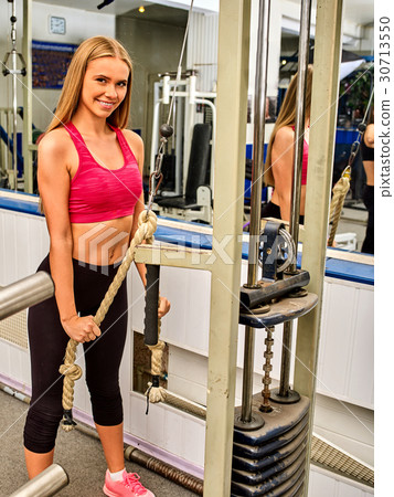 圖庫照片: girl workout on bicep curl machine in sport gym.