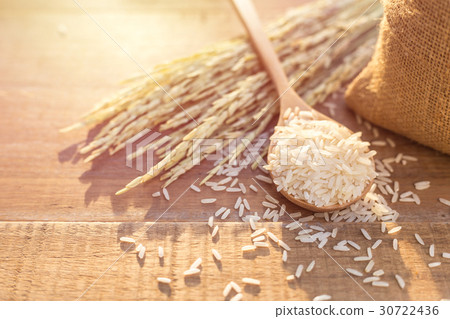 Thai jasmine rice in spoon and small sack on wooden table background 30722436