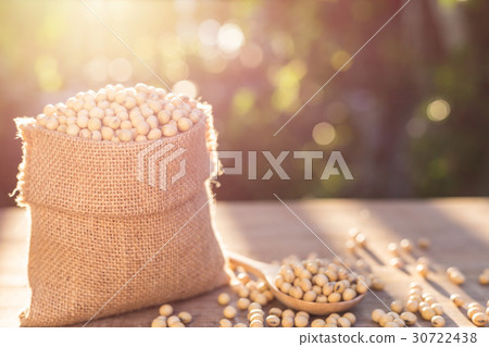 Soybean in small brown sack on wooden table. Outdoor shooting with sunlight and green blur bokeh and lens flare effect background 30722438