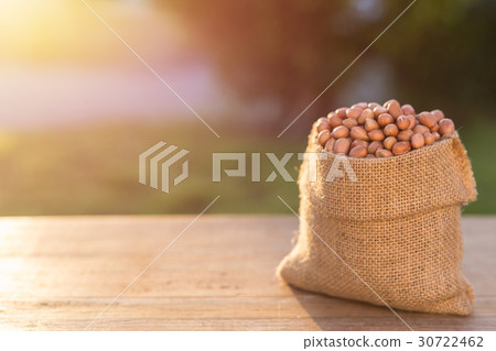 Peanut in small sack on wooden table. Outdoor shooting with sunlight and blur background Peanut in small sack on wooden table. Outdoor shooting with sunlight and blur background 30722462