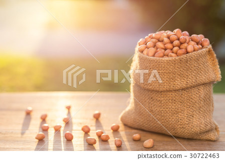 Peanut in small sack on wooden table. Outdoor shooting with sunlight and blur background 30722463