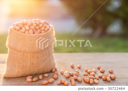 Peanut in small sack on wooden table. Outdoor shooting with sunlight and blur background Peanut in small sack on wooden table. Outdoor shooting with sunlight and blur background 30722464