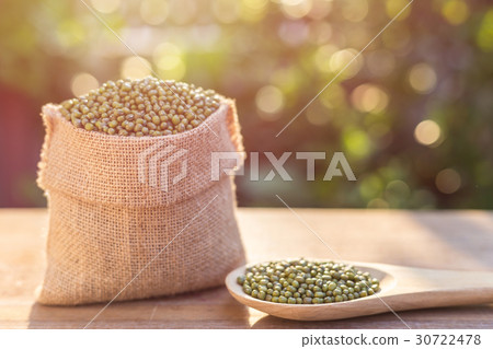Mung beans in small wooden sack on wooden table. Outdoor shooting with sunlight and green blur bokeh and lens flare effect background 30722478