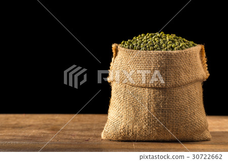 Mung beans in small wooden sack on wooden table. Isolated on black background Mung beans in small wooden sack on wooden table. Isolated on black background 30722662