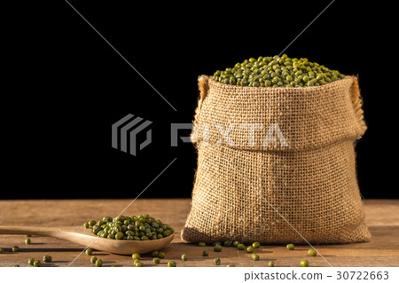 Mung beans in small wooden sack on wooden table. Isolated on black background 30722663